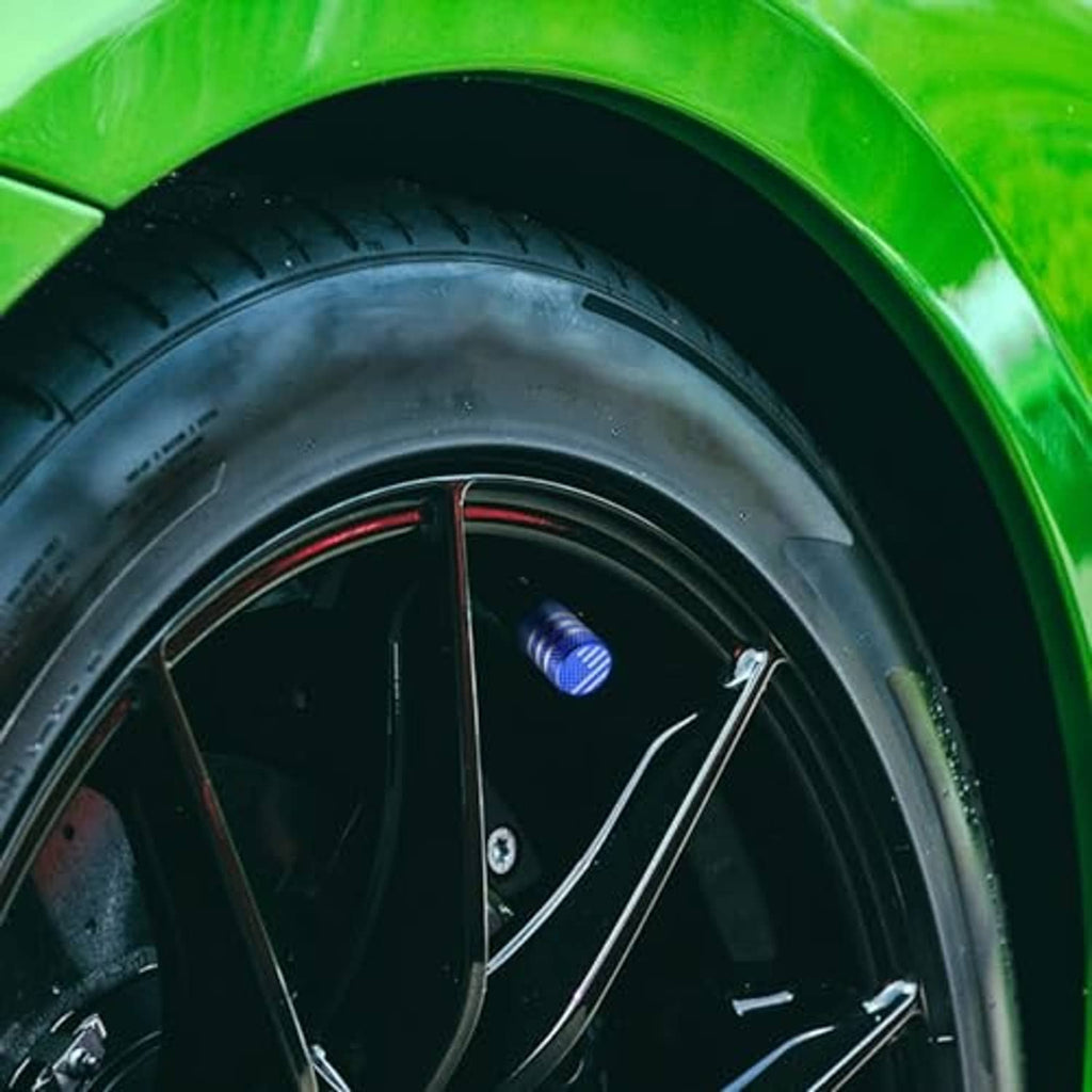 Blue American flag tire valve stem cap on a black wheel valve stem