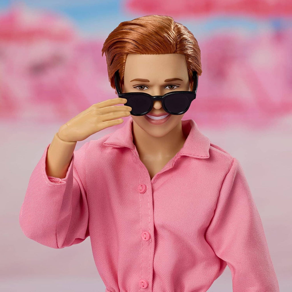 Collectible doll portrait with brown hair, pink shirt, and black sunglasses