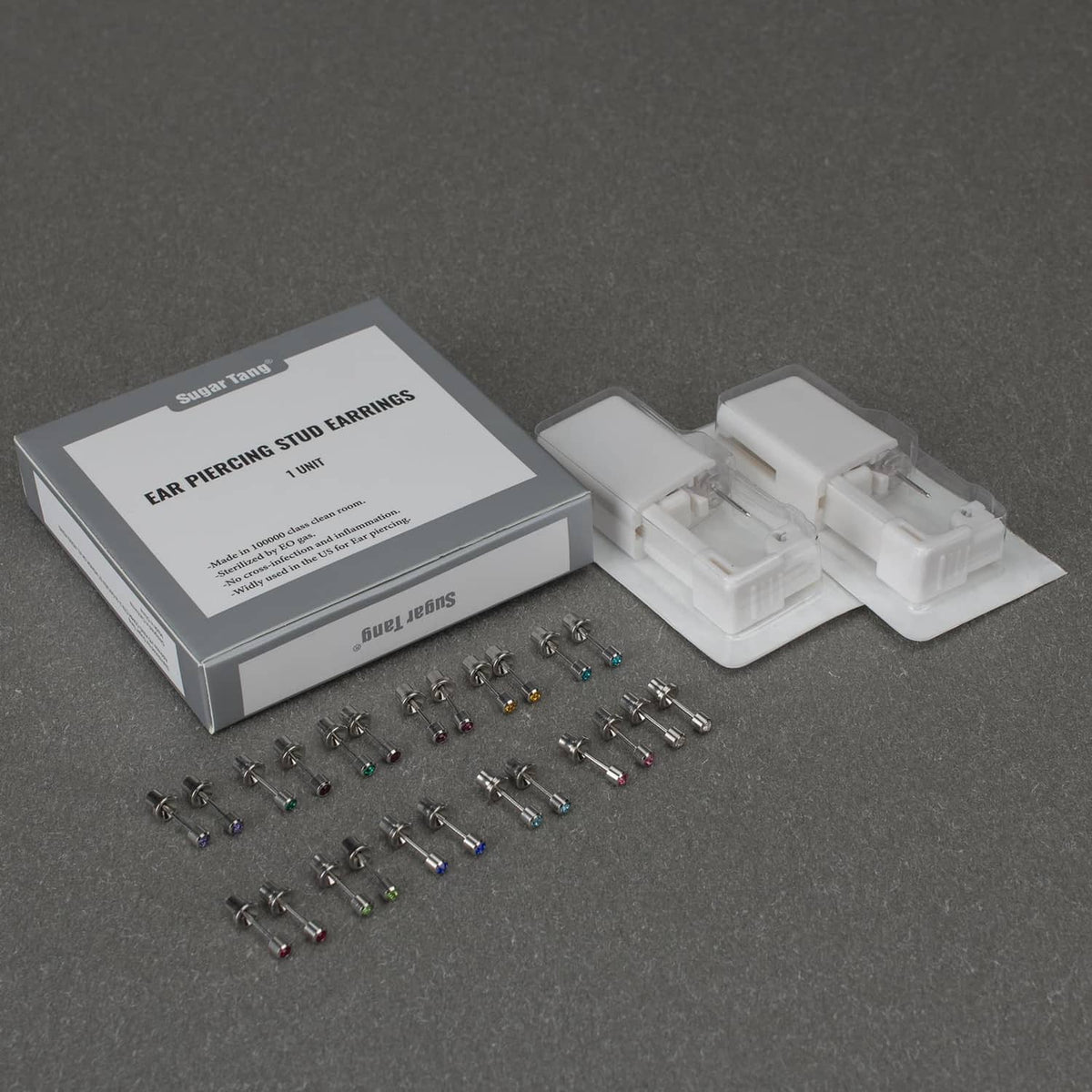 Ear piercing kit box with loose stud earrings and disposable gun cartridge pieces