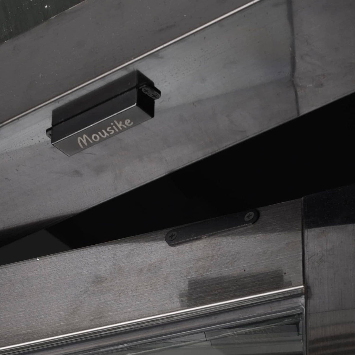 Black magnetic door catch on cabinet frame with latch bar and screws