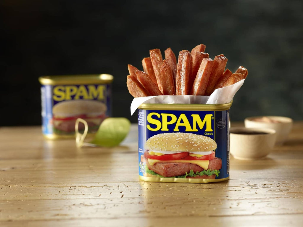 SPAM Classic can on a table next to a serving with fries and sandwich