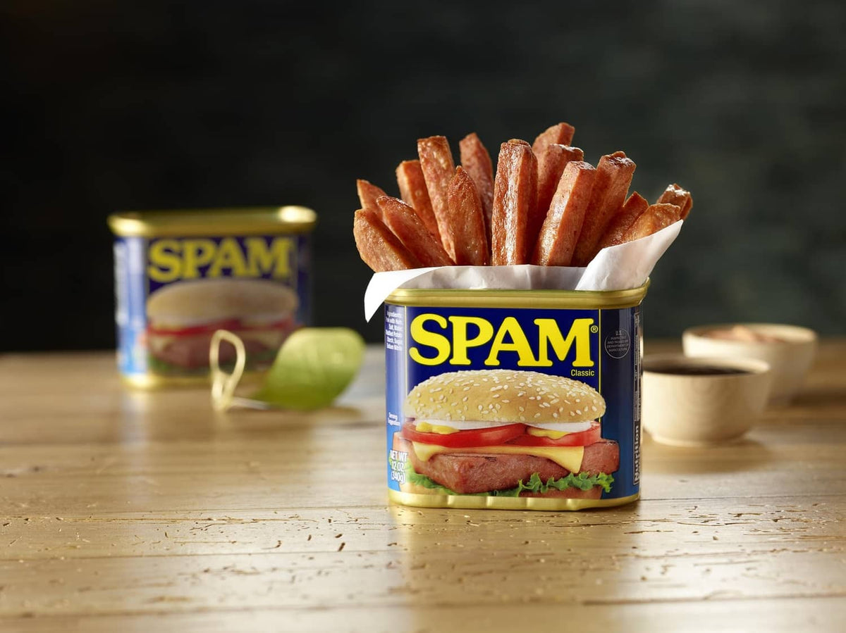SPAM Classic can on a table next to a serving with fries and sandwich