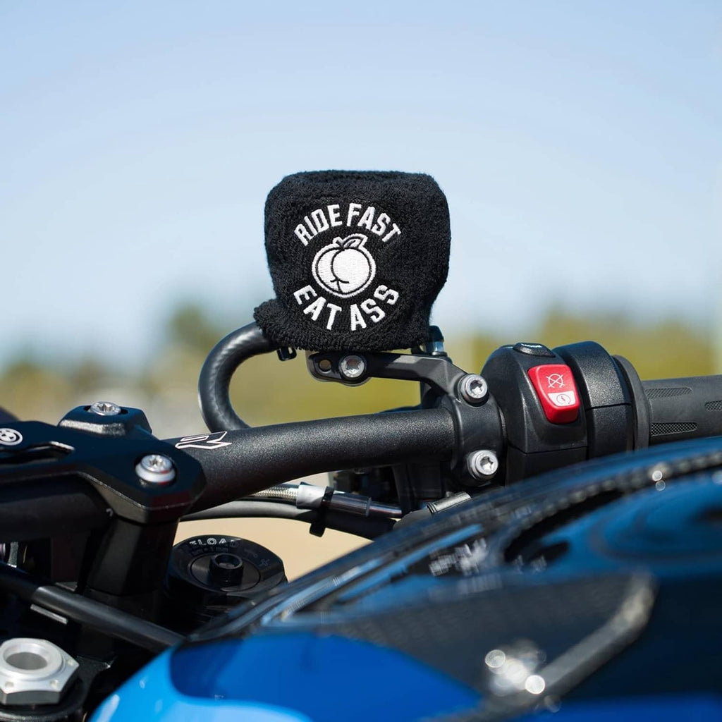 Black knit brake fluid reservoir cover sock with “RIDE FAST EAT ASS” logo, near switch