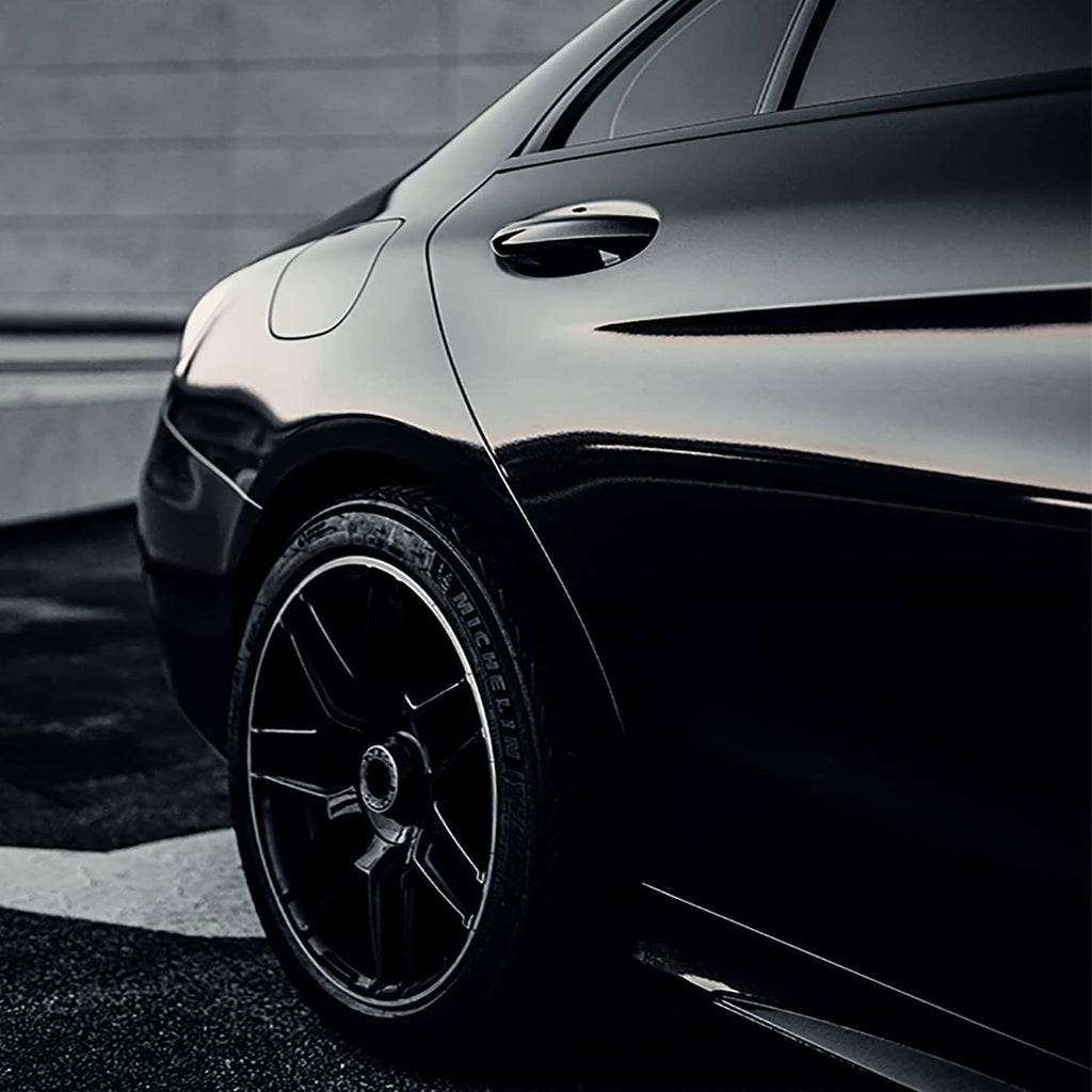 Gloss black vinyl wrap applied to a car front fender and wheel