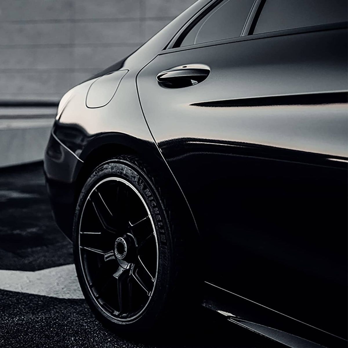 Gloss black vinyl wrap applied to a car front fender and wheel
