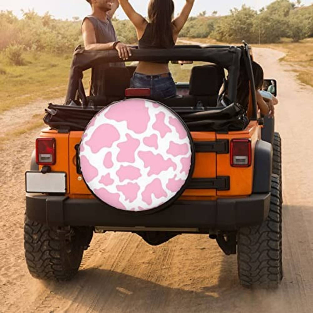 Pink cow-print spare tire cover mounted on an orange off-road vehicle, round cover