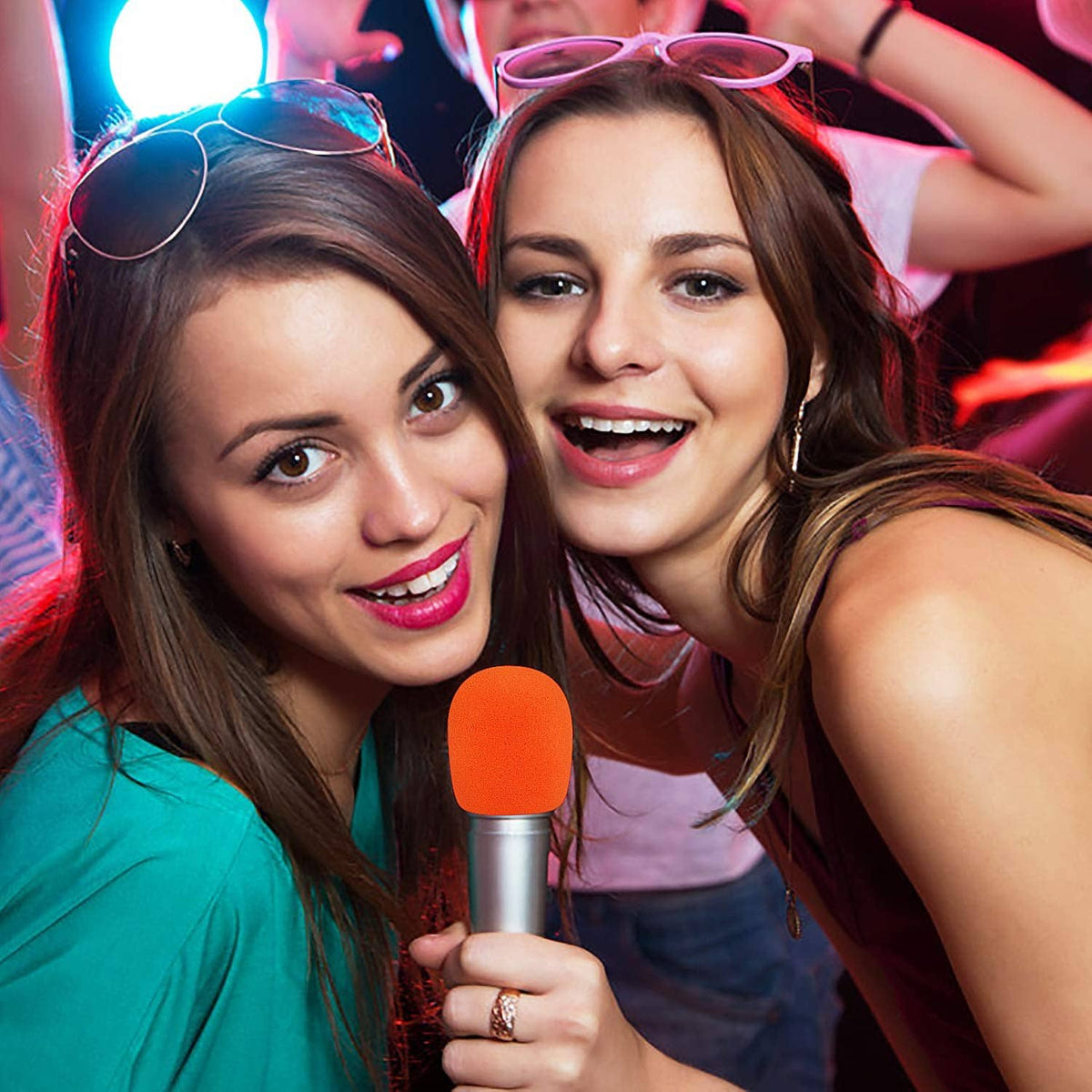 Orange foam microphone cover on handheld mic held by partygoers