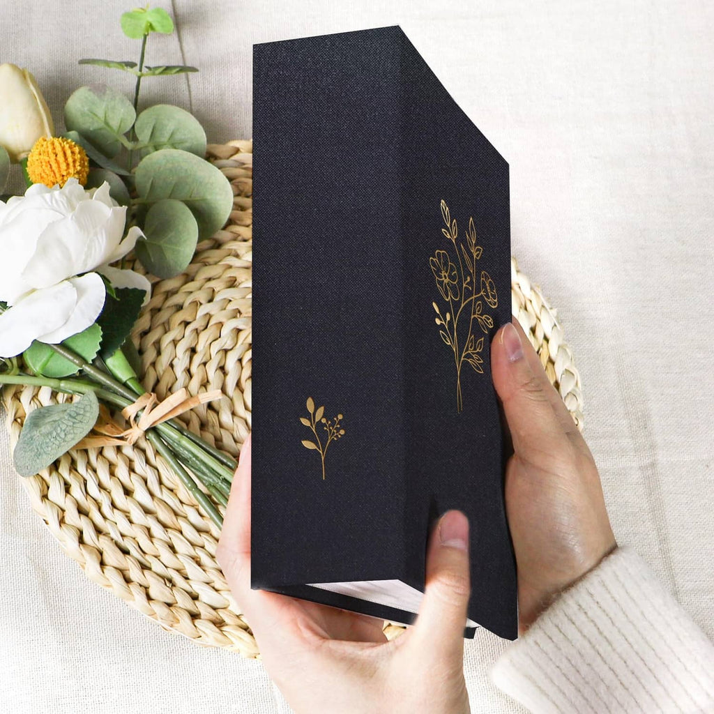 Black photo album with gold floral tree motif, shown from the side