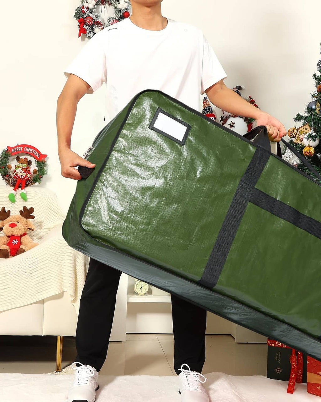 Green Christmas tree storage bag held by a person, large zipped fold-up cover.