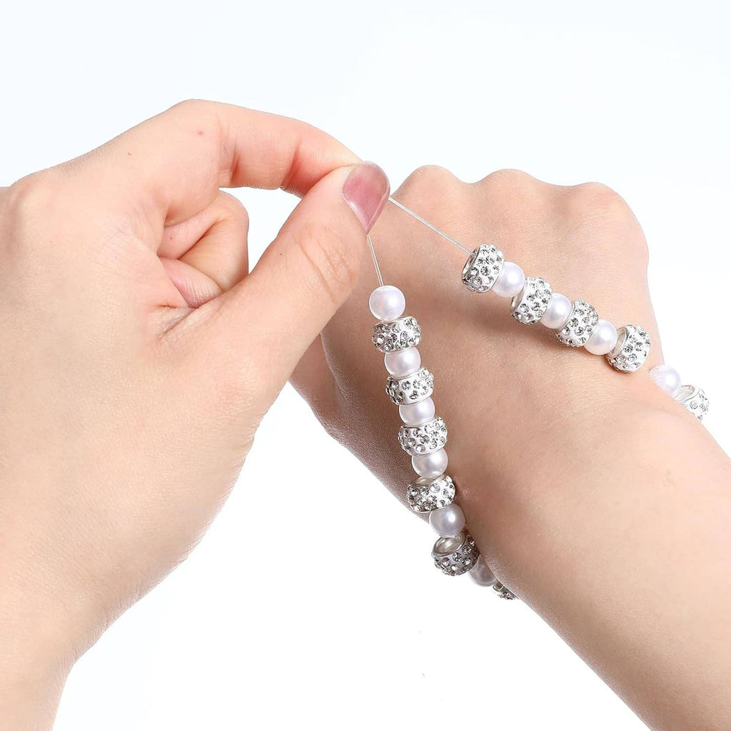 Hands pulling white elastic string through pearl and silver bead bracelet