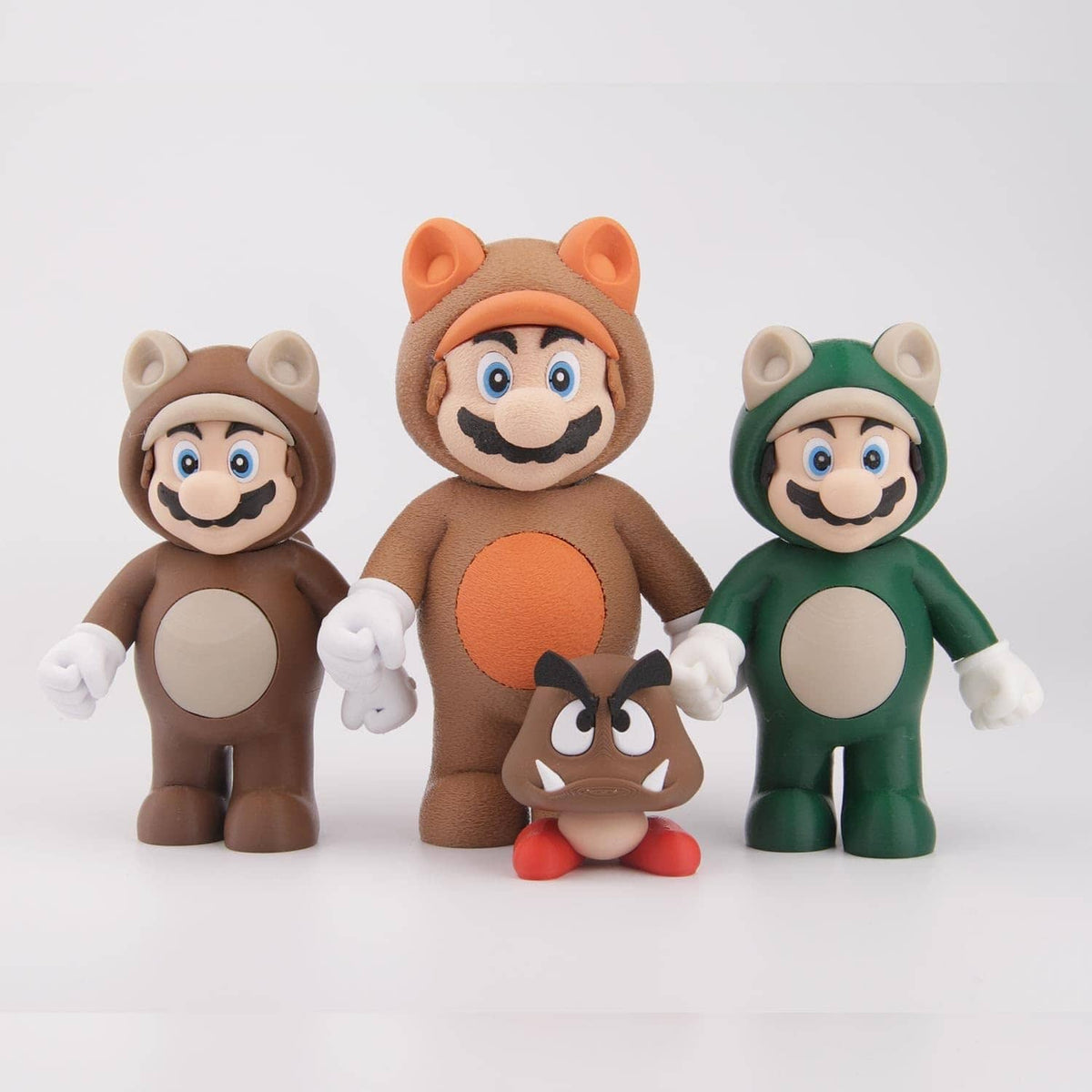 Set of brown, orange, and green 3D printed character figures with rounded heads and hands.