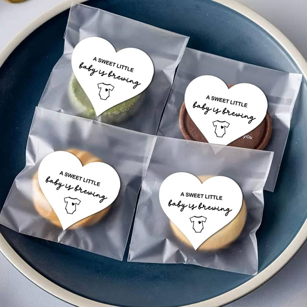 Assorted heart-shaped stickers reading “A SWEET LITTLE baby is brewing” with baby onesie