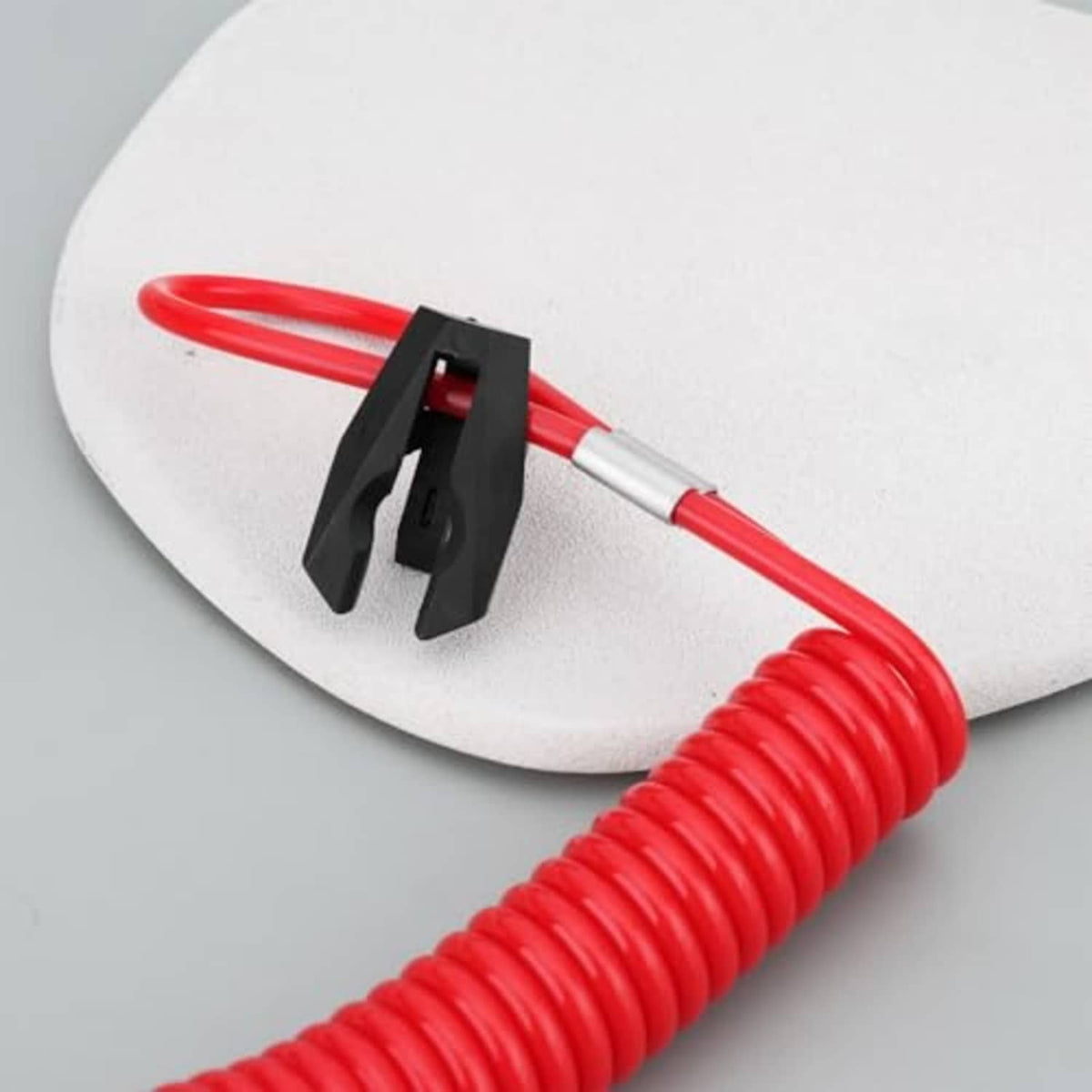 Red coiled emergency kill switch lanyard with black clamp and red loop