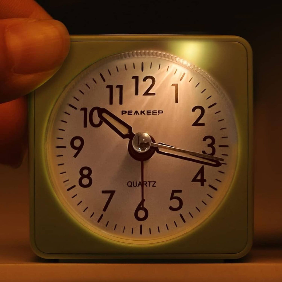 Mint teal travel alarm clock with illuminated analog dial and quartz markings
