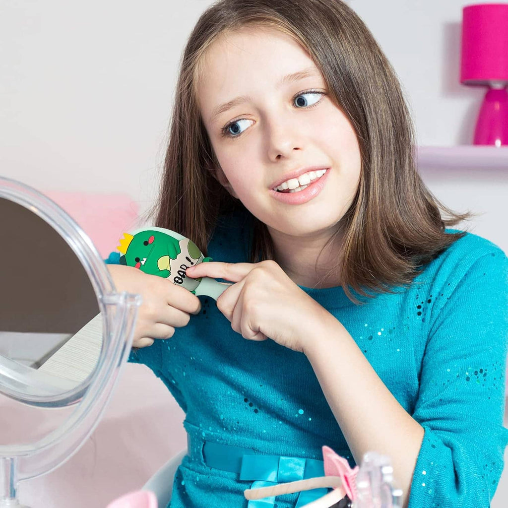 Child using a mini mint hair brush with green dinosaur detail on the handle