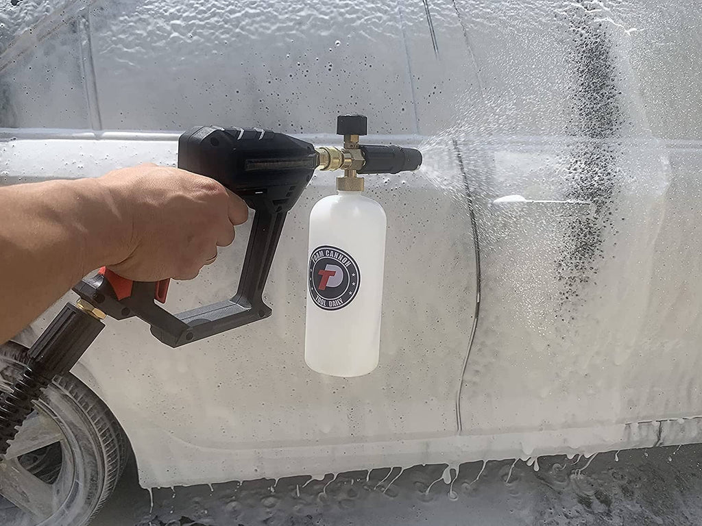 Hand holding pressure washer foam cannon gun with white foam bottle