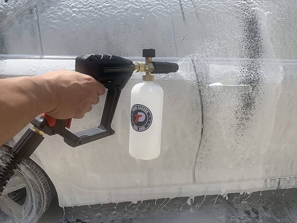 Hand holding pressure washer foam cannon gun with white foam bottle