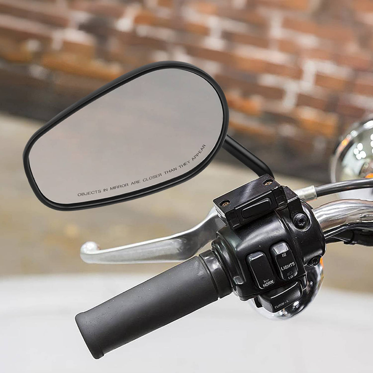 Black rearview mirror mounted on motorcycle handlebar with oval reflective glass