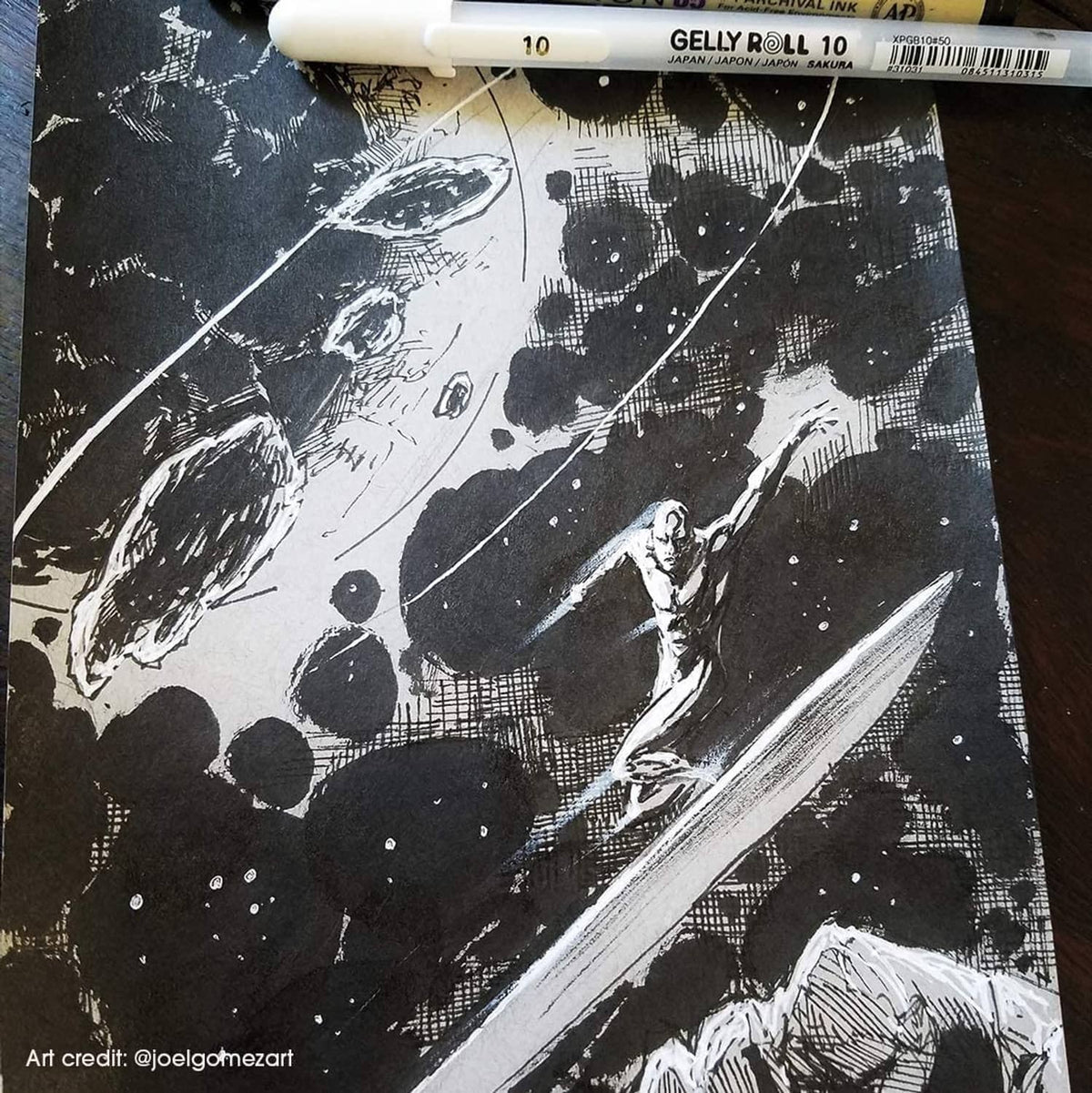 White gel pen making bold opaque ink marks on dark textured paper.
