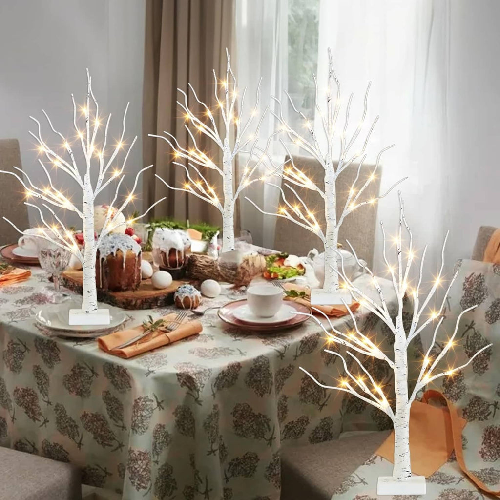 Lighted birch tree centerpiece with white trunks and warm LED lights on dining table