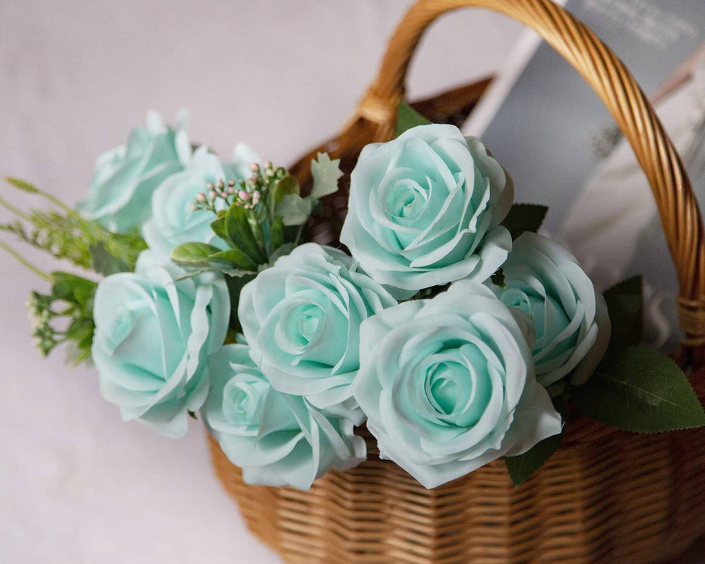 Teal blue artificial rose flowers with green leaves in a wicker basket