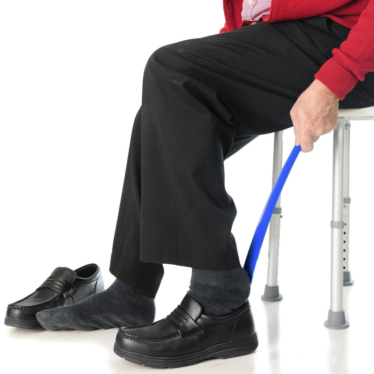 Blue reaching grabber in use near black socks and shoes on a support stool