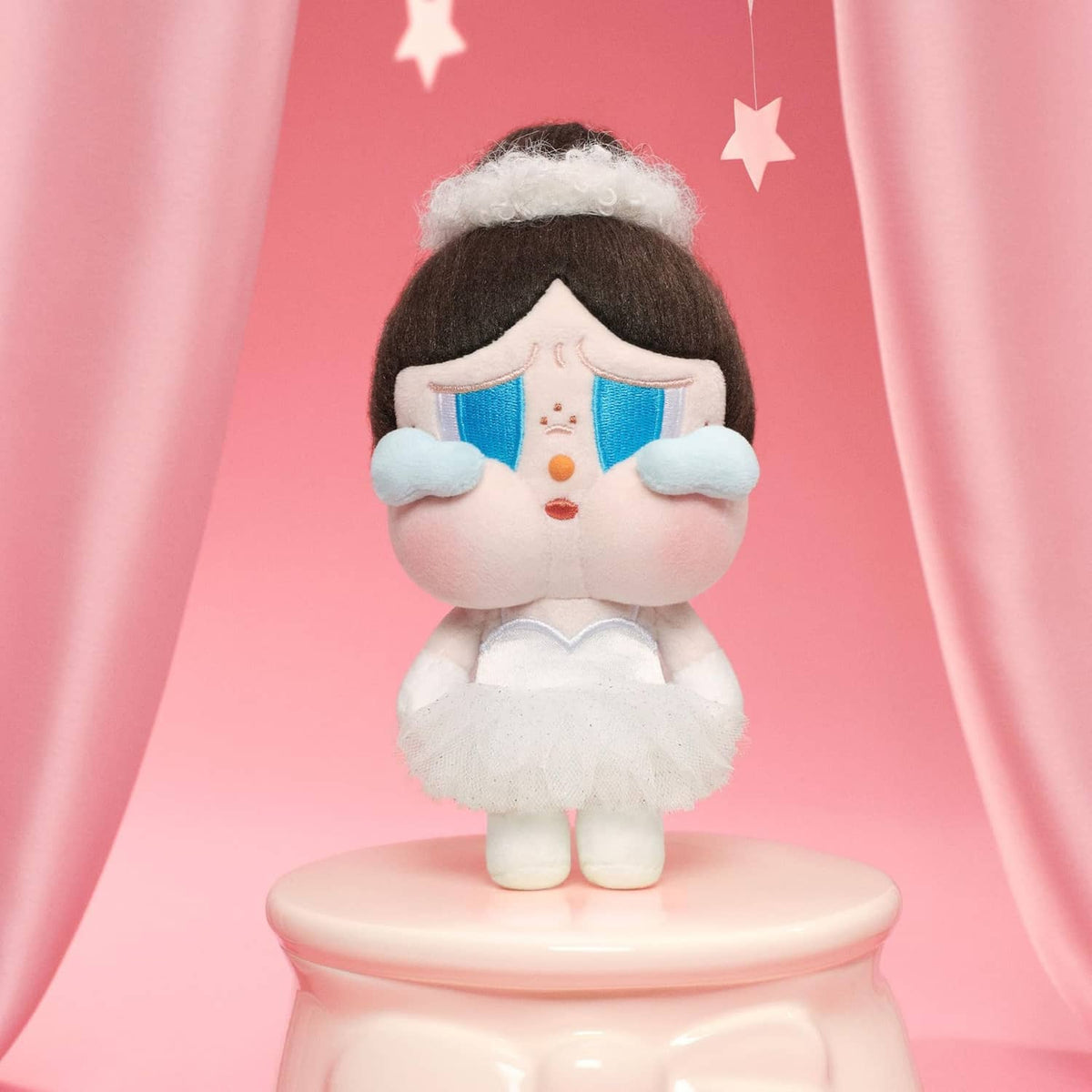 Plush doll pendant with dark hair, blue ear patches, white ruffled dress