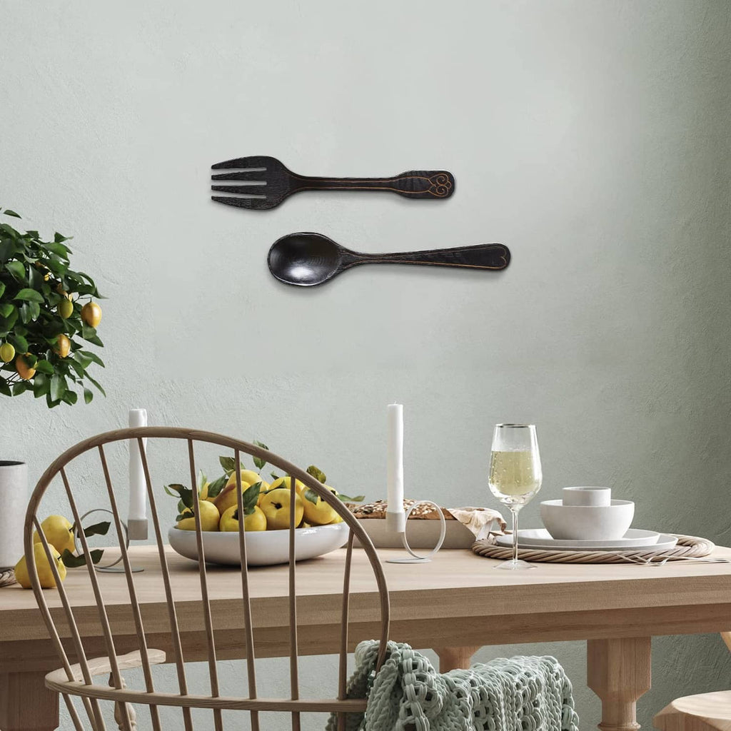 Dark metal fork and spoon wall decoration, mounted separately on a light wall