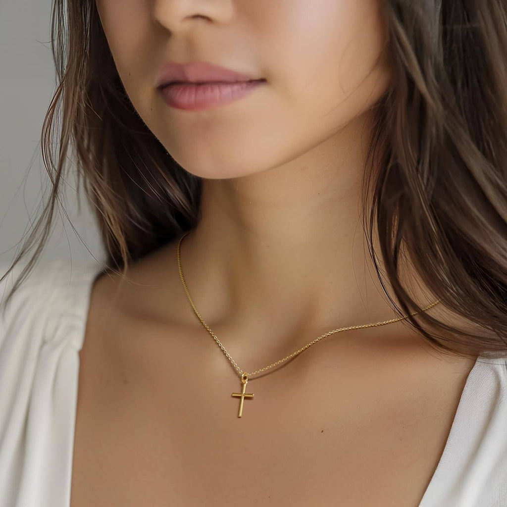 Gold-tone cross pendant necklace with thin chain, centered at neckline