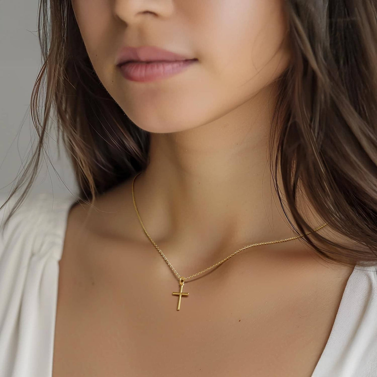 Gold-tone cross pendant necklace with thin chain, centered at neckline