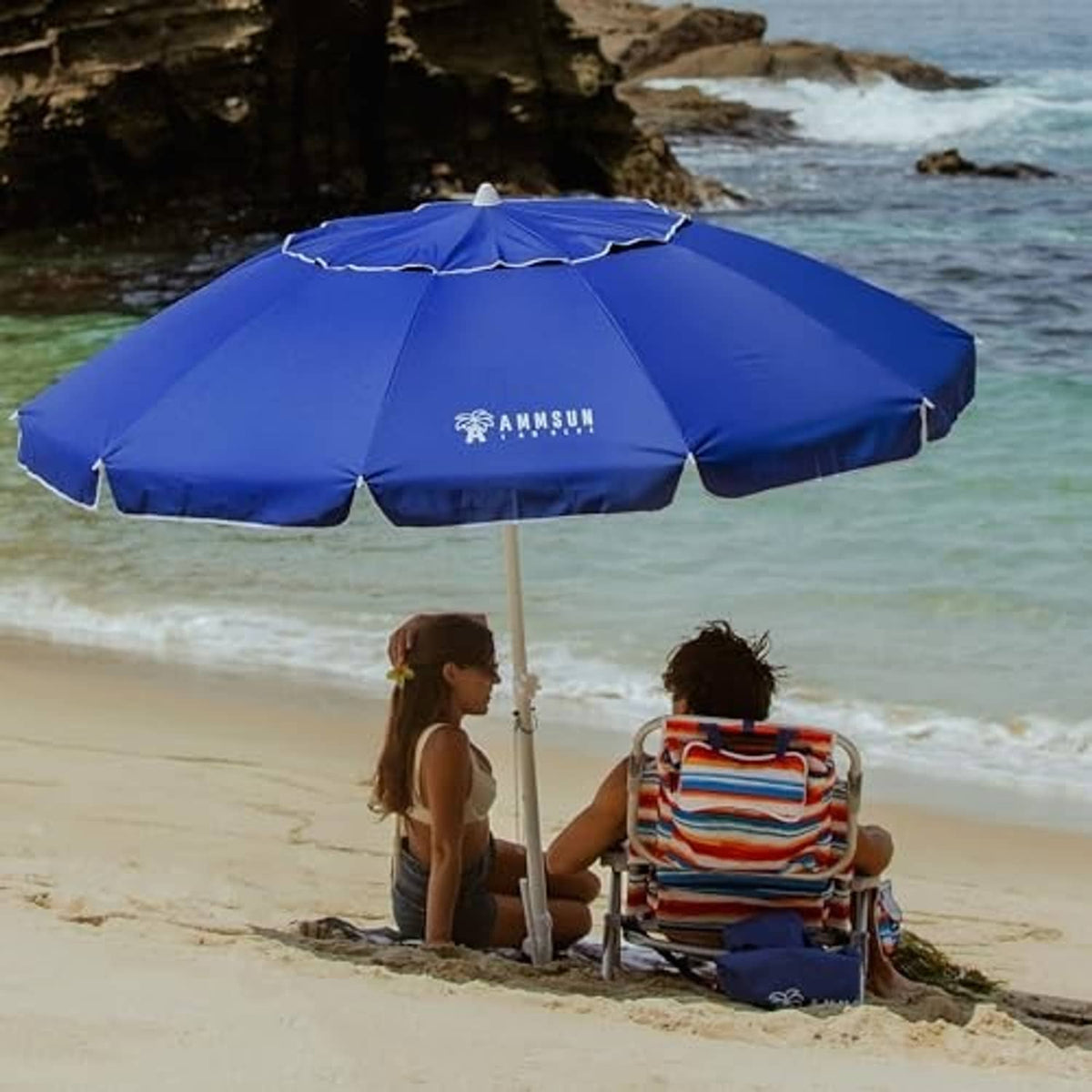 Blue beach umbrella open on sand with central pole and vented canopy ribs
