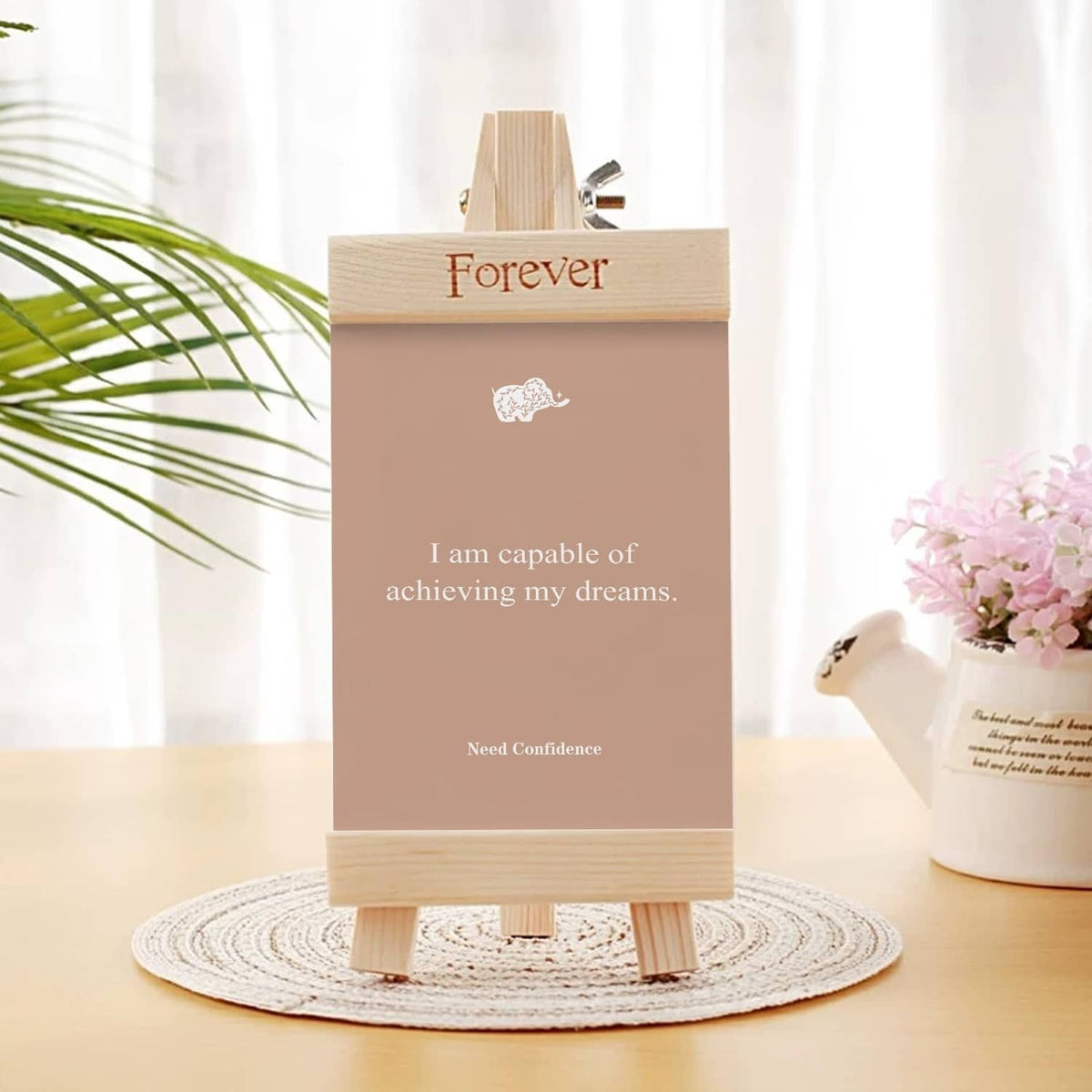 Pink affirmation card on easel reading “I am capable of achieving my dreams”