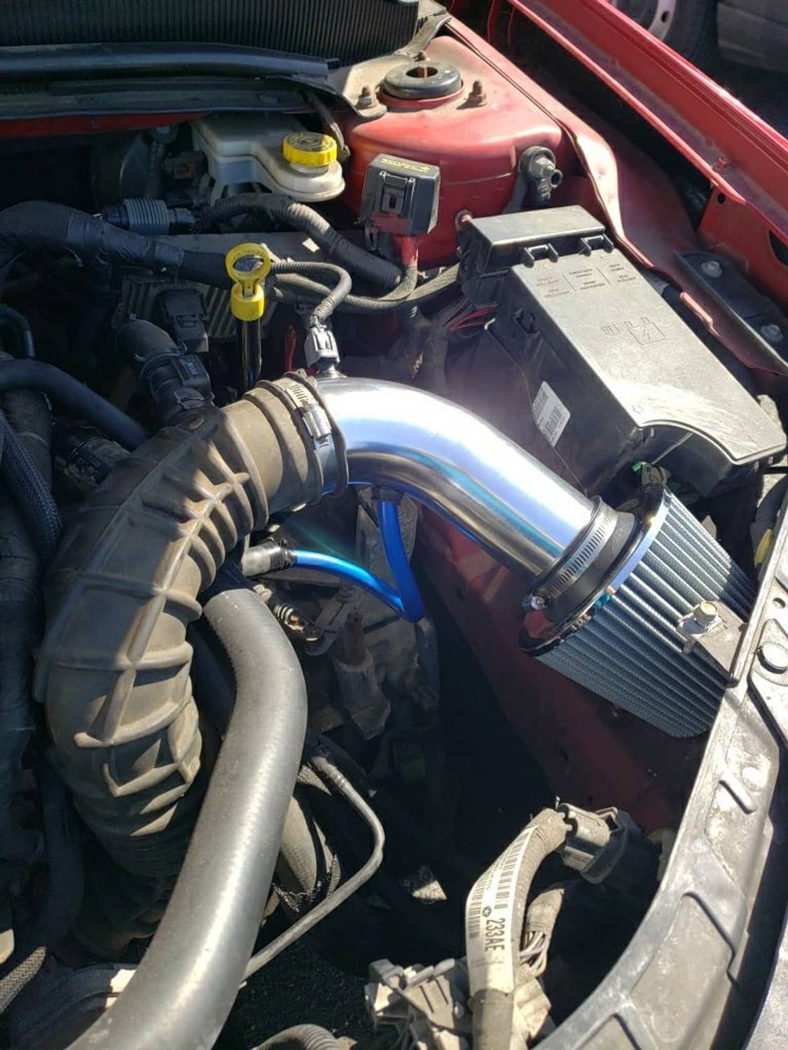 Cold air intake filter kit installed in engine bay: chrome pipe, black filter, blue hose