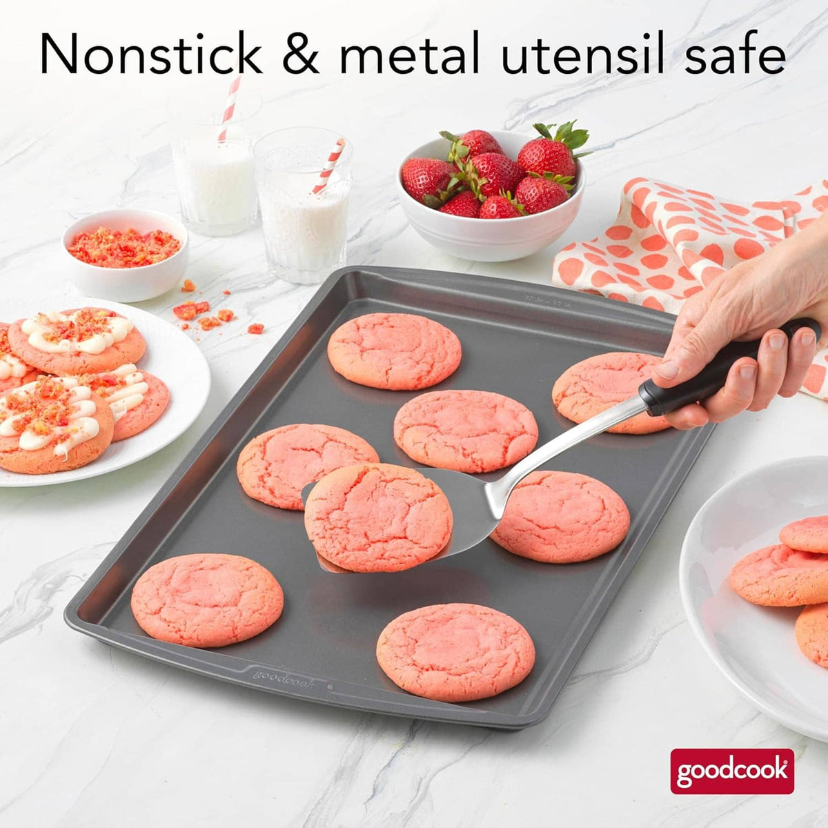 Gray nonstick baking sheet with cookie dough rounds, metal utensil nearby