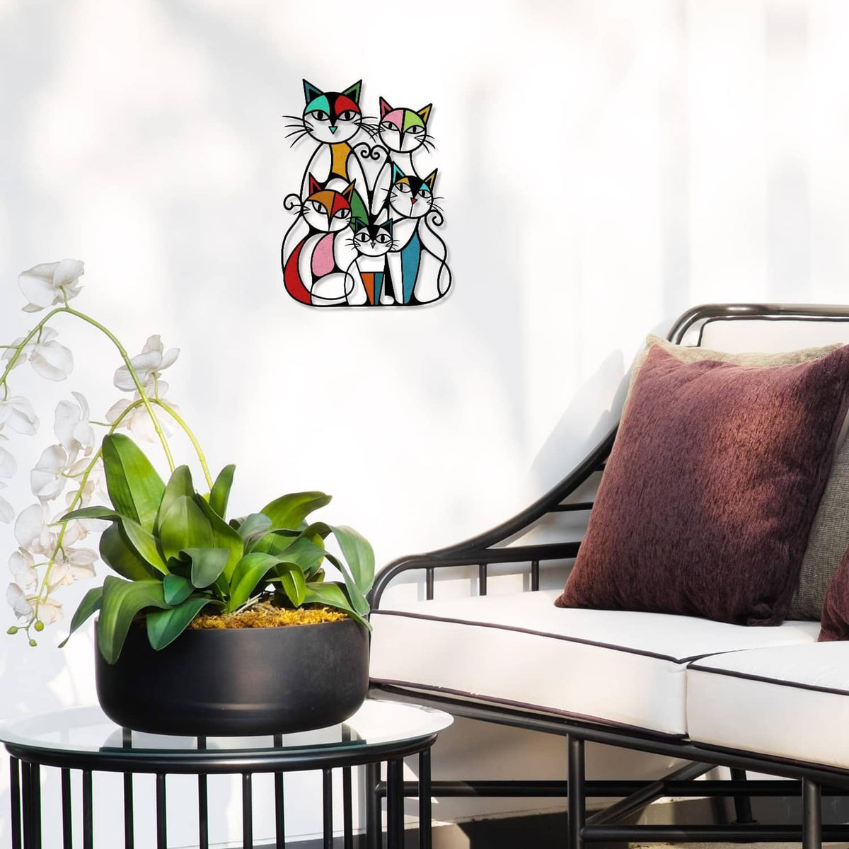 Colorful metal cat wall art with five retro cats on a wall above seating