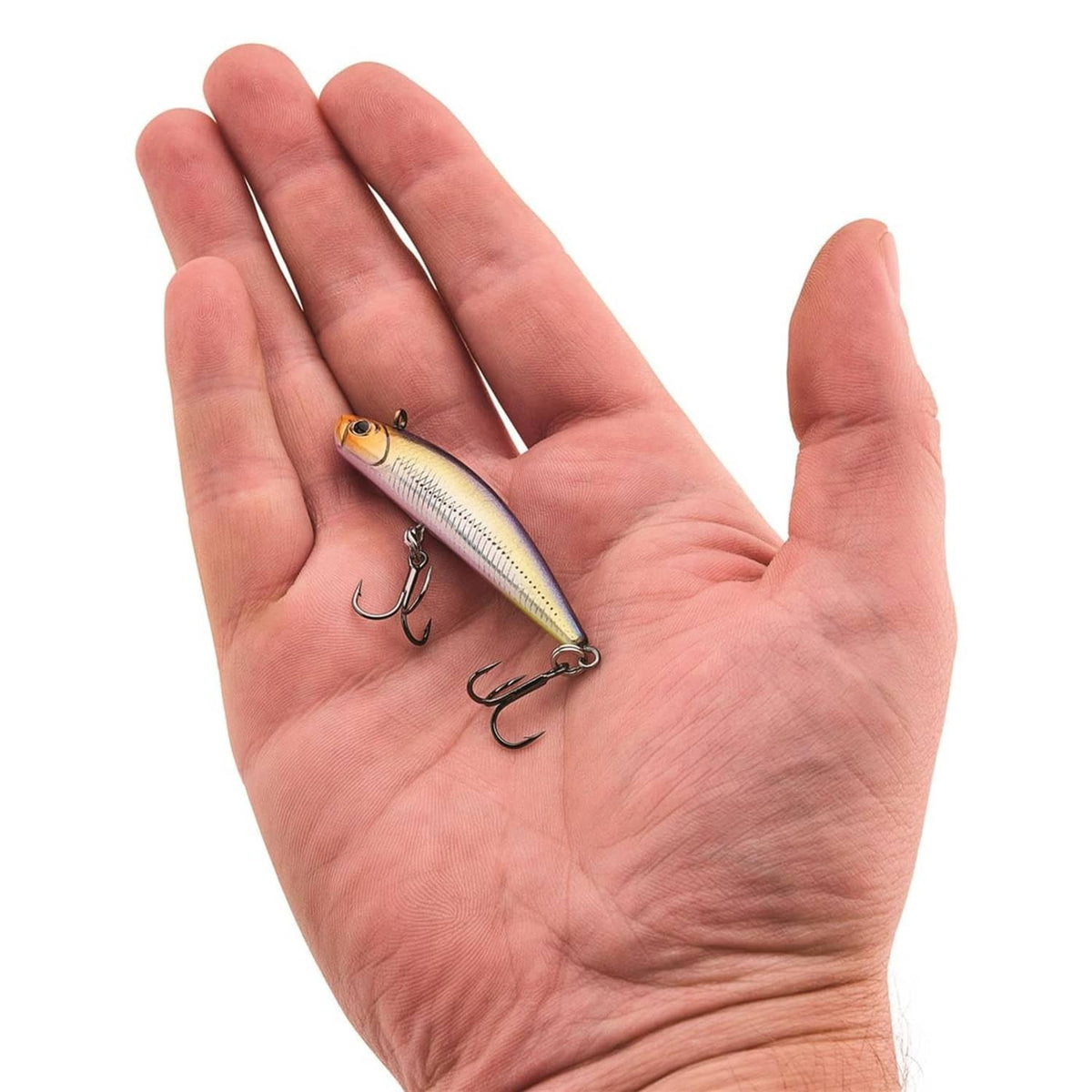 Fishing lure with pale belly and blue back, held in hand with two treble hooks