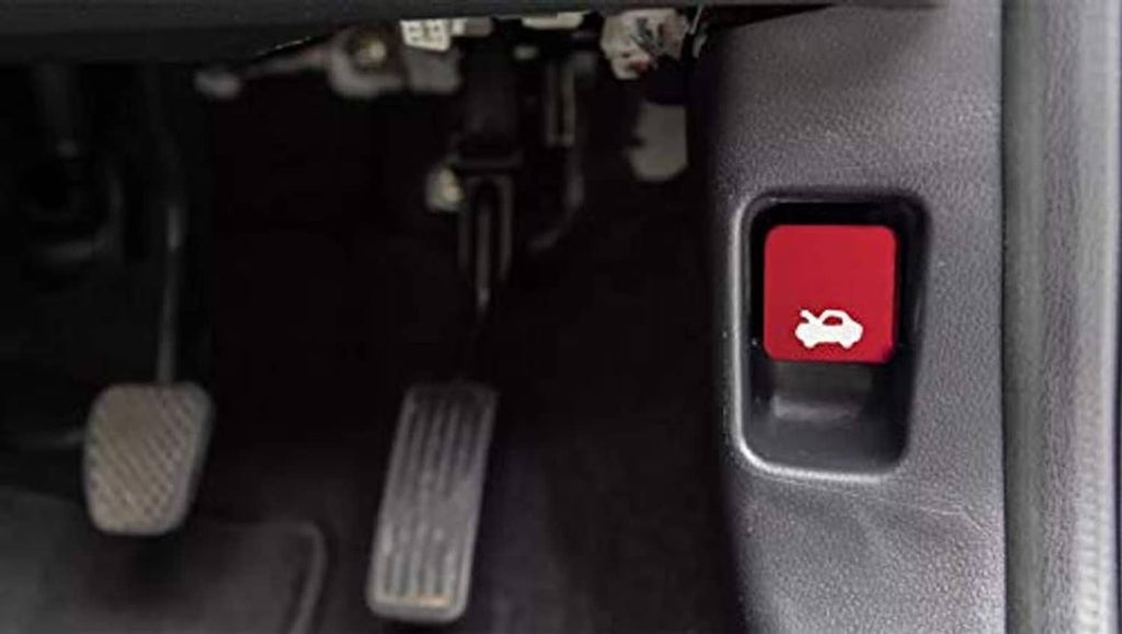 Red hood latch release handle button with wrench icon on dark interior panel.