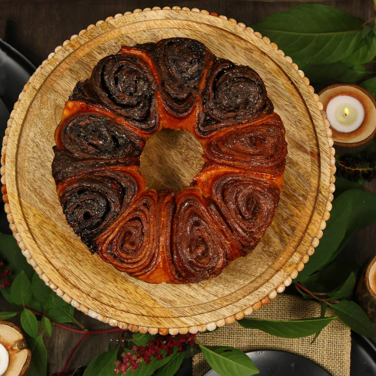 Chocolate and cinnamon babka cake with spiral swirls on a round wooden board