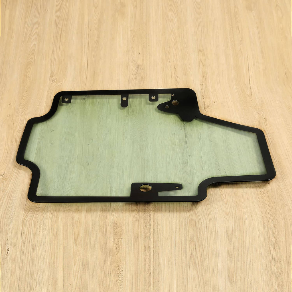 Skid steer door glass panel with black frame, top mounting holes, light blue tint