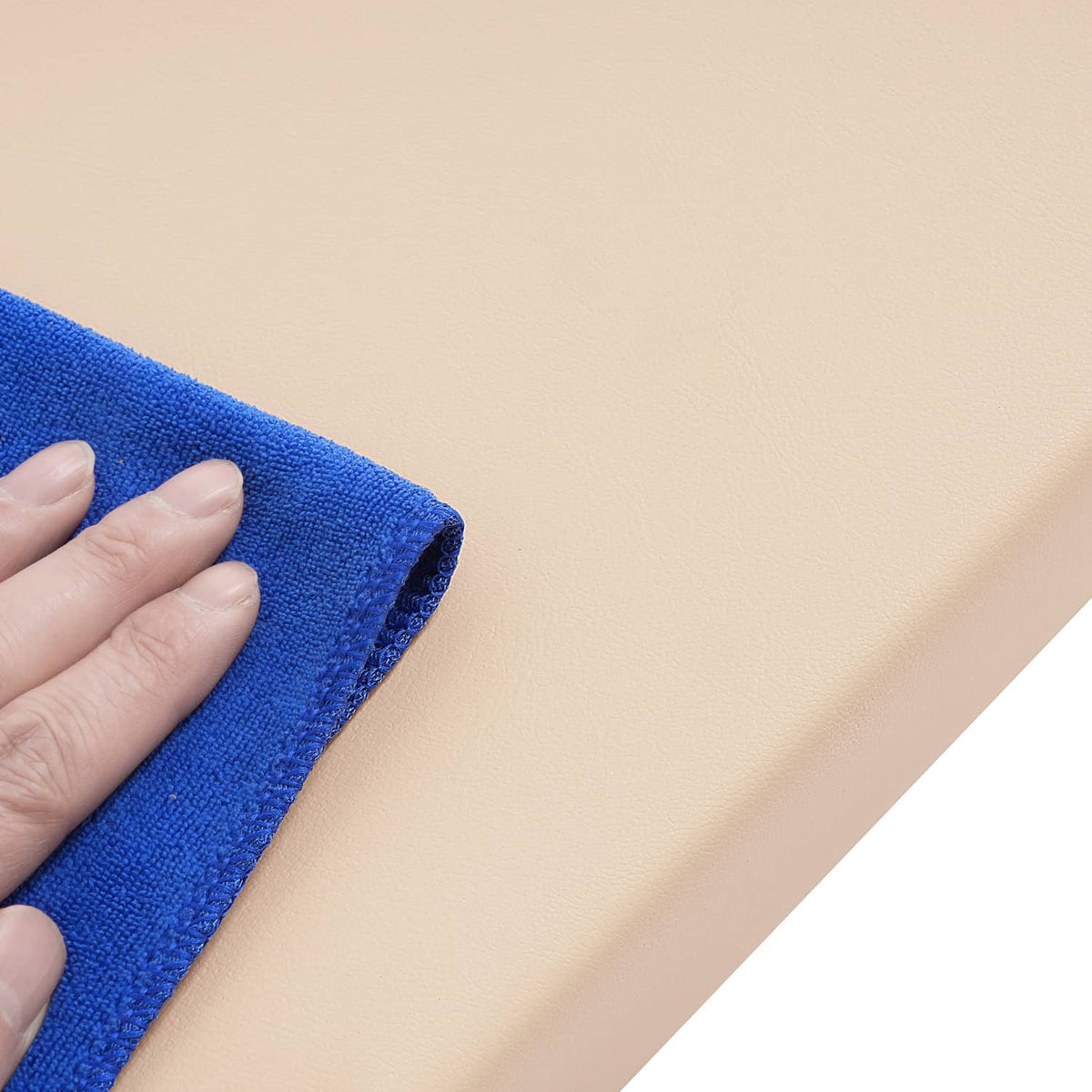 Beige seat back cushion being wiped with a blue cloth by hand