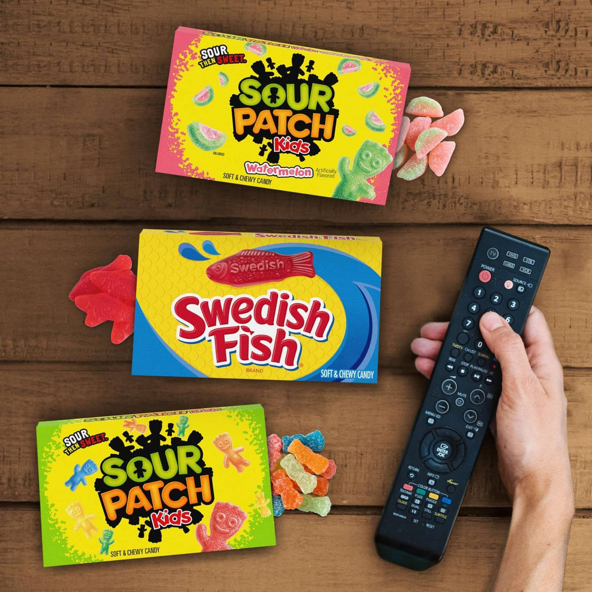 Sour Patch Kids and Swedish Fish candy boxes on table with TV remote