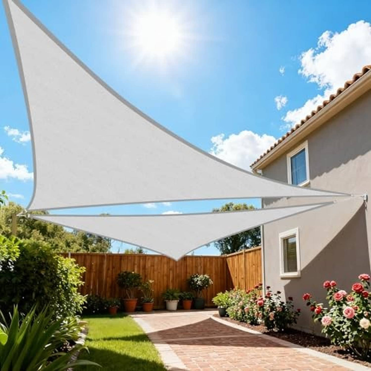 Light grey triangular sun shade sail over a backyard walkway with curved edge