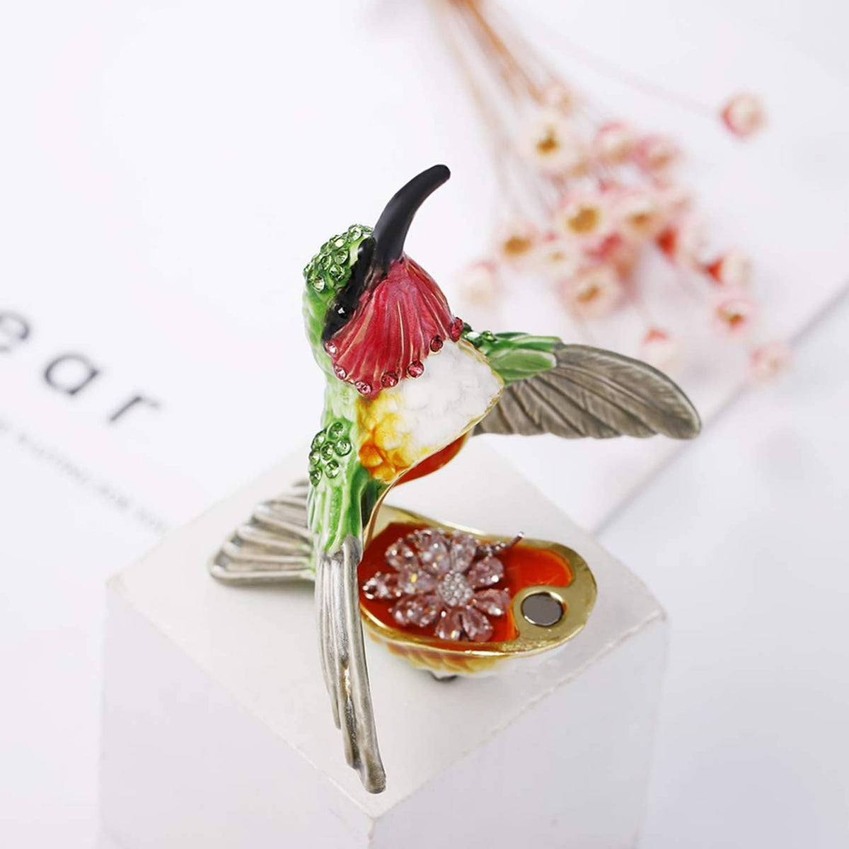 Hinged enamel hummingbird trinket box, green bird perched over open compartment