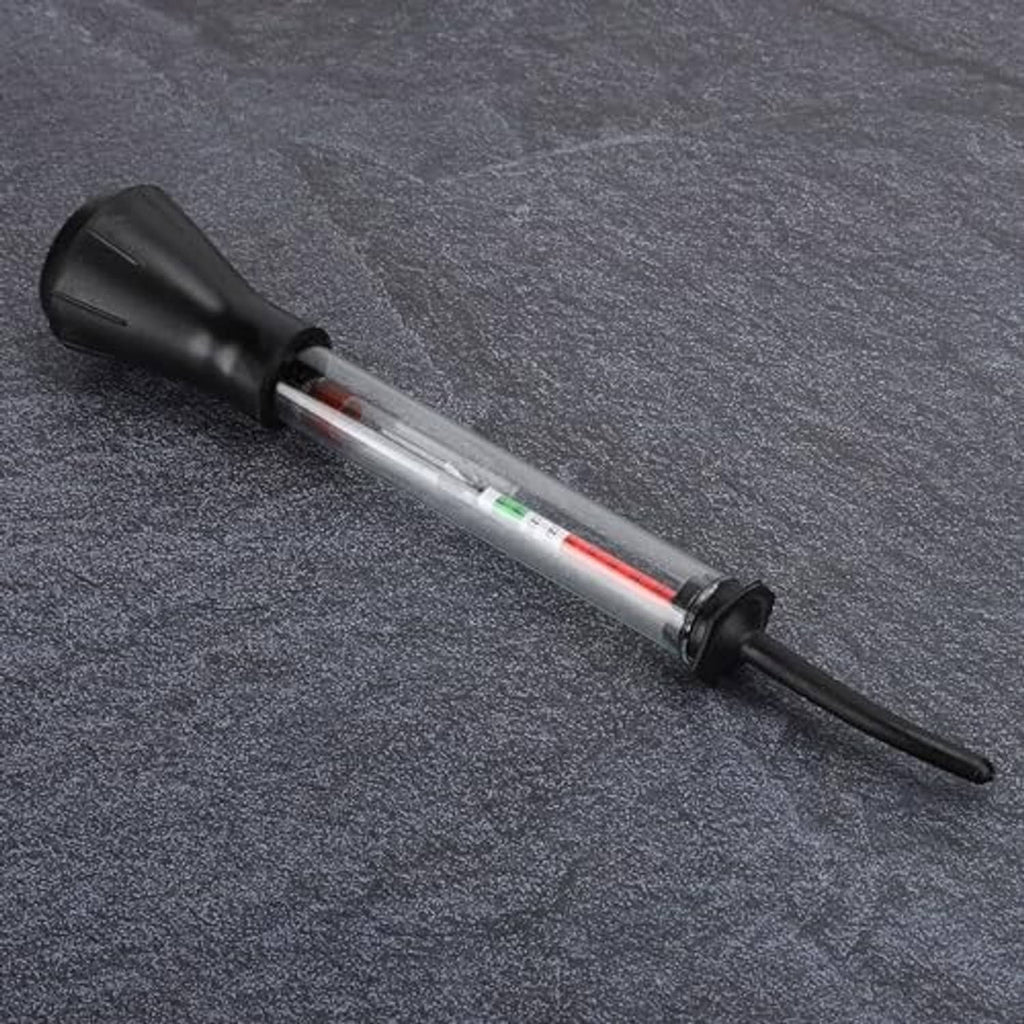 Battery hydrometer tester lying on textured surface, clear tube with red fluid indicator