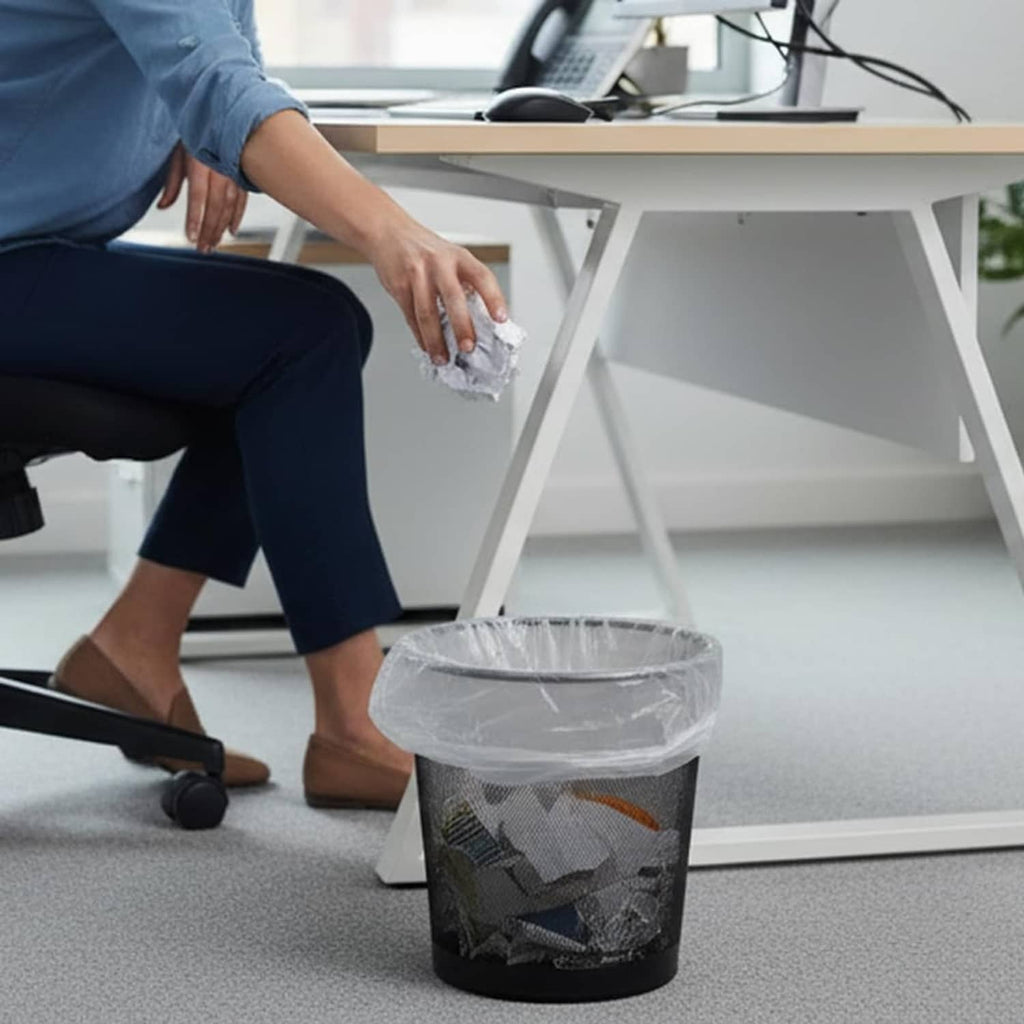 Clear trash bag liner pulled up by hand over a black trash can