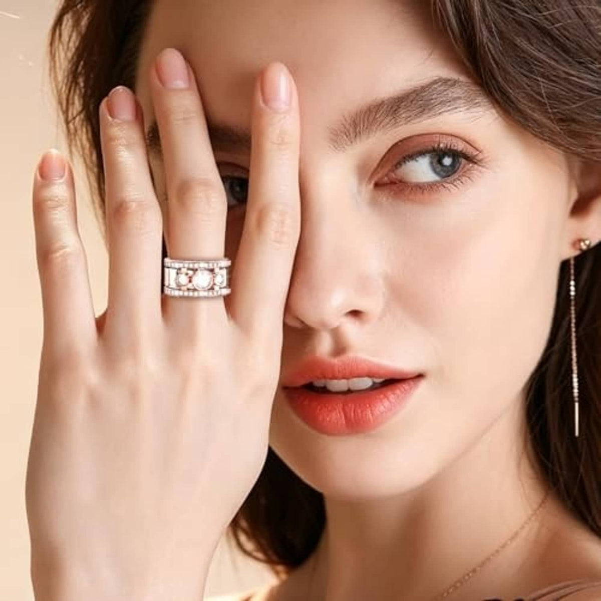 Rose gold-tone ring on hand with three small crystal squares and center round stone