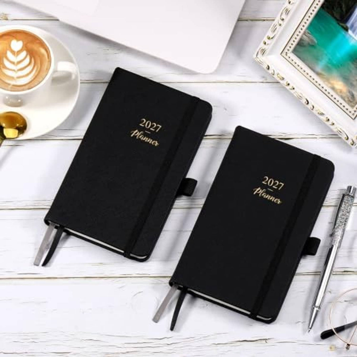 Two black 2027 pocket planners with gold title, side pen loop, and elastic closure
