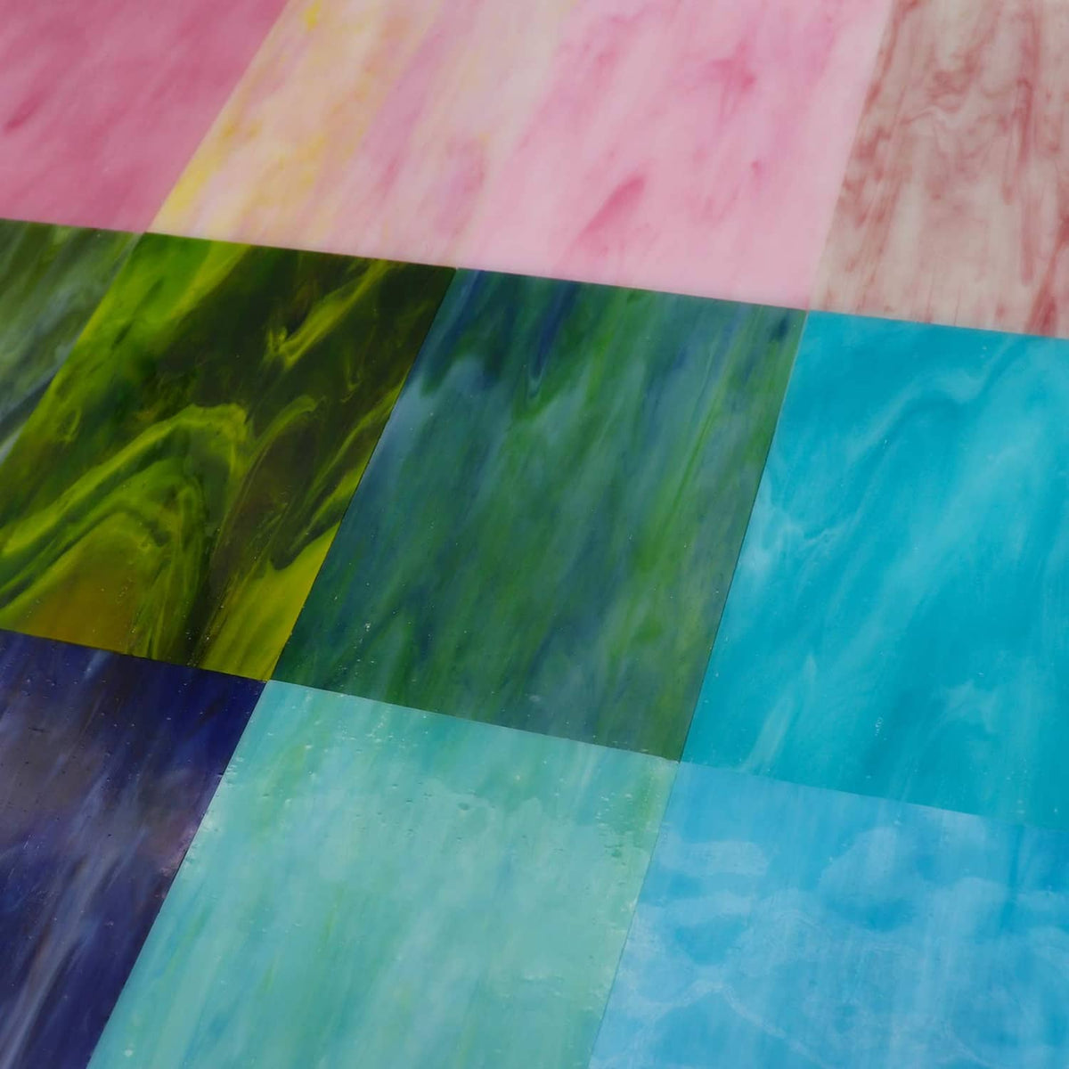 Stained glass mosaic sheet close-up, overlapping rectangular pieces with blue and pink