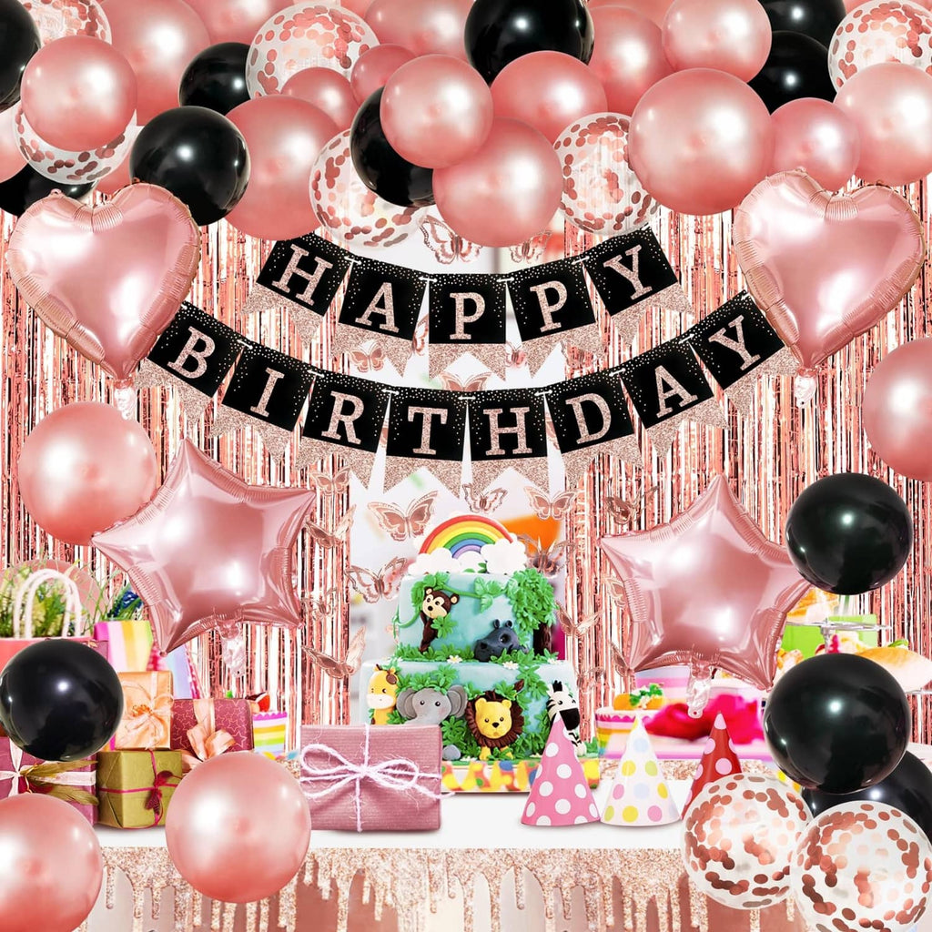 Happy Birthday banner with rose gold and black balloon arch over a decorated gift table