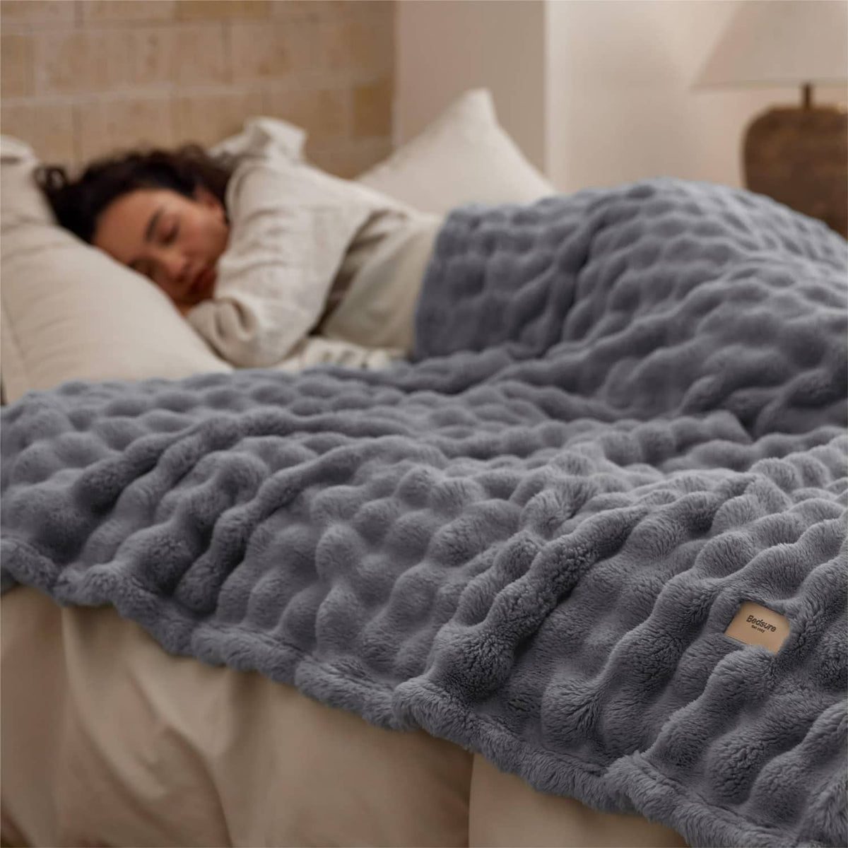 Gray 3D bubble fleece blanket laid on a bed, plush raised texture